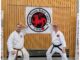 von links: Belal Chahrour und Paul Miller. Zwei alte Karateka Freunde aus Studienzeiten in der Sochin dachi Stellung vor dem Logo des Karate Verein Bebra.