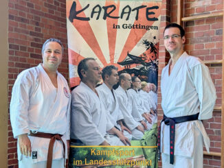 Rot-Weiß Kassel Spartenleiter Karate Belal Chahrour und Trainer Volker Vogel neben dem Banner des ausrichtenden Vereins